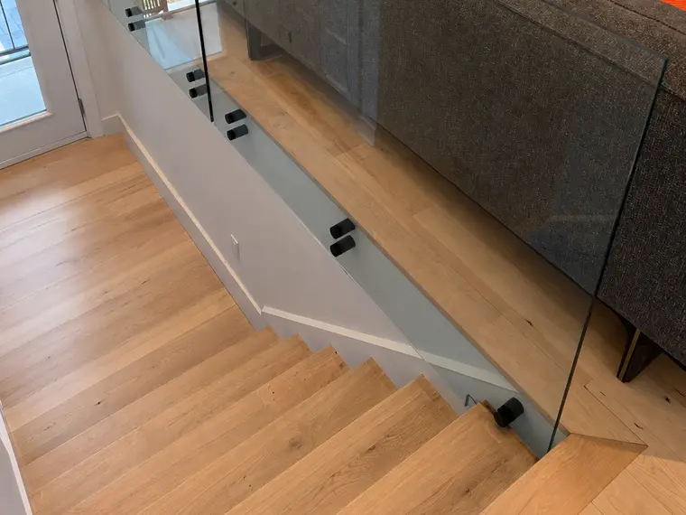 Garde-corps en verre le long d'un escalier intérieur, pinces noires.