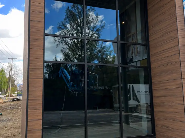 Mur-rideau vitré d'un bâtiment commercial, aluminium noir et bois.